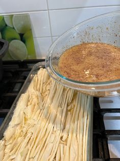 a glass bowl filled with food sitting on top of a stove next to a pan