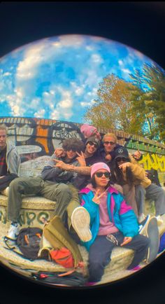 a group of people sitting on top of a skateboard ramp in front of graffiti covered walls