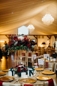 the table is set with gold plates and red flowers