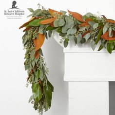 a wreath with orange and green leaves is hanging on the side of a white wall