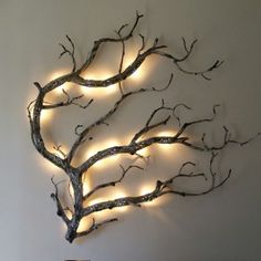 a metal tree with lights on it in the shape of a heart is shown against a white wall