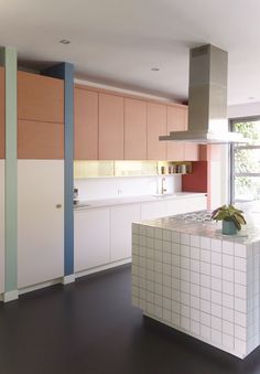 a modern kitchen with an island counter and stove top oven in the center, surrounded by multicolored cabinets