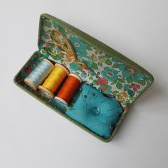 an open sewing kit with spools of thread and scissors