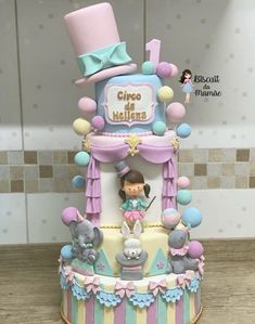 a multi layer cake with an elephant and girl on top, decorated in pastel colors