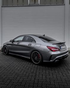 a mercedes benz coupe parked in front of a white building with black rims and red brake pads