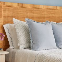 a bed with blue and white pillows on it's headboard next to a night stand