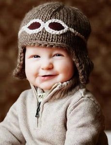 a baby wearing a knitted hat and smiling