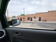 a view from the inside of a car looking at an empty street and brick building