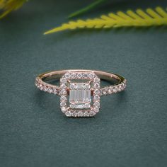 an emerald cut diamond ring on a green surface