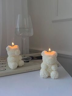 two white teddy bears sitting on top of a table next to a glass of wine