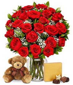 a teddy bear sitting next to a vase filled with red roses and chocolate candies