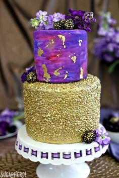 a three tiered cake with purple and gold decorations