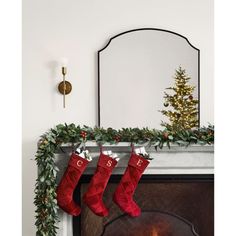 christmas stockings hanging from a mantel over a fire place with a mirror above it