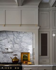 a kitchen with marble counter tops and gold accents on the hood, cabinets, and stove