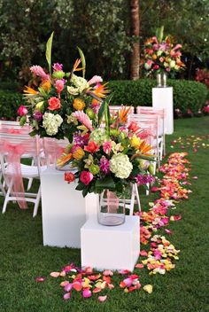 an outdoor ceremony set up with flowers and petals on the ground in front of rows of chairs