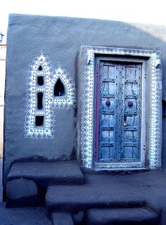 an artisticly designed door and bench in front of a stucco wall with decorative designs