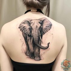 an elephant tattoo on the back of a woman's shoulder