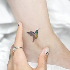 a small hummingbird tattoo on the side of a woman's right leg and foot