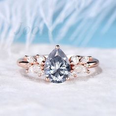 an engagement ring with a pear shaped diamond surrounded by three smaller pear - shaped diamonds