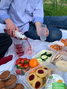 a man is sitting on the ground with food and drinks in front of him,