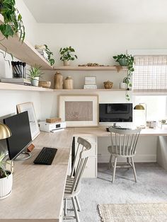 a desk with a computer on top of it next to two chairs and a window