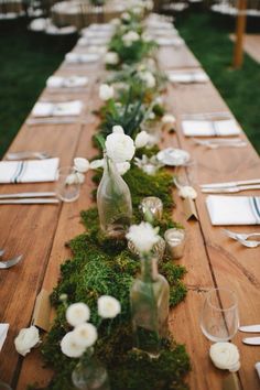 the long table is covered with moss and white flowers