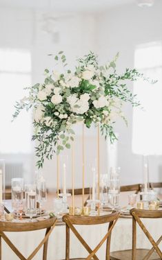 an elegant centerpiece with white flowers and greenery