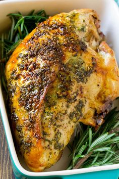 a close up of a chicken in a casserole dish with herbs and seasonings