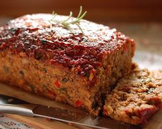 sliced meatloaf sitting on top of a cutting board next to a knife