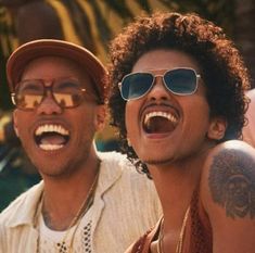 two men wearing sunglasses and hats are laughing