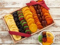 an assortment of fruit in a wooden box with a red ribbon on the top and bowl next to it