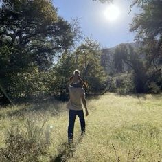 a man standing in the middle of a field with trees and grass on both sides