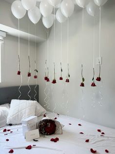 white balloons are suspended from the ceiling above a bed with red flowers and roses on it