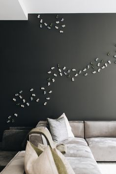 a white couch sitting in front of a gray wall with flowers on the back side