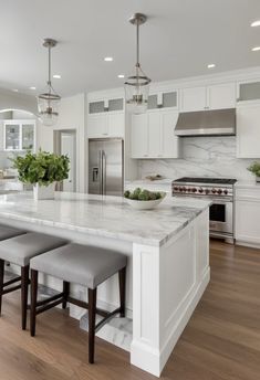 a large kitchen with white cabinets and marble counter tops, an island in the middle