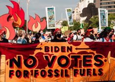 a group of people holding signs and flags in front of a building with flames on it