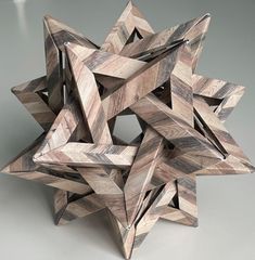 a wooden object made out of wood pieces on a gray surface with one star in the center