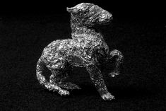 a silver dog statue sitting on top of a black surface