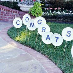 there are some signs that say congrats on the grass in front of a brick walkway