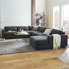 a living room with a large sectional couch and coffee table on the floor in front of it