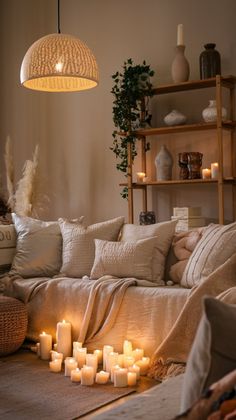 a living room filled with lots of candles and pillows on top of a couch next to a book shelf