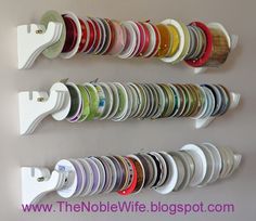 there is a wall mounted rack that has many different colored cups on it and the bottom one in white