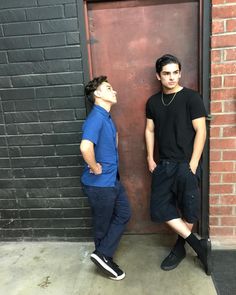 two young men standing next to each other in front of a door