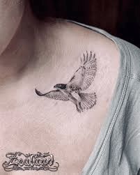 a woman's chest with a bird tattoo on it