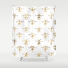 a white shower curtain with gold bees on it