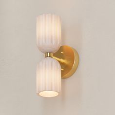 two light fixtures mounted on the wall in a white and gold color scheme with dim lighting