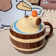 a ceramic cup with an orange on top sitting in front of a keyboard and mouse