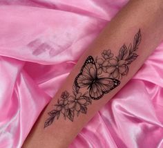 a woman's arm with a butterfly and flowers tattoo on it