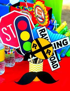 a red table topped with lots of signs and paper hats on top of it's head