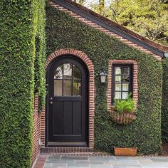 a house covered in green ivy with a black door and window on the front side